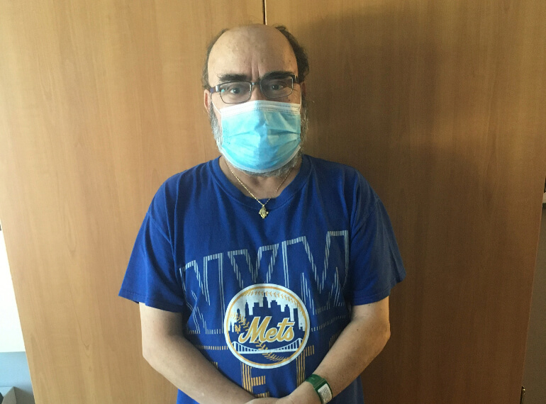 Yiotis standing in front of his hospital room door wearing a mask.
