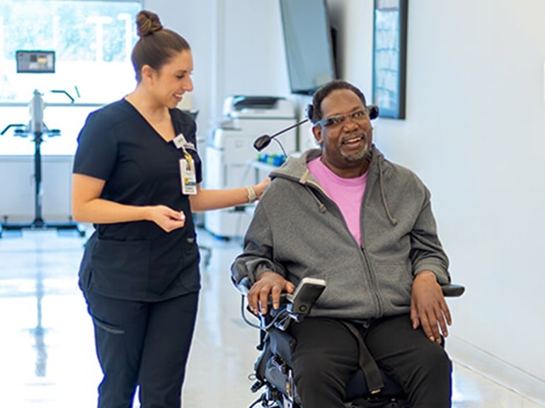 A spinal cord injury patient in a wheelchair working with physical therapist.
