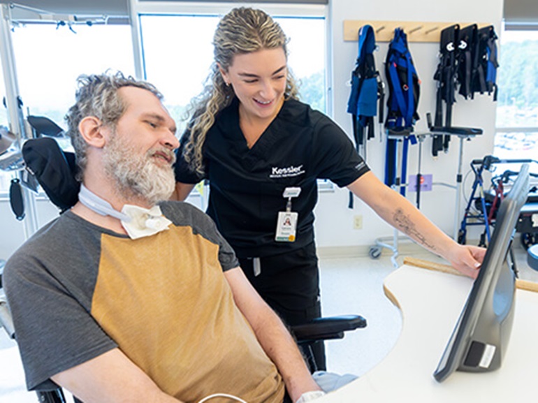 Female brain injury rehabilitation therapist works with adult male patient on reading skills