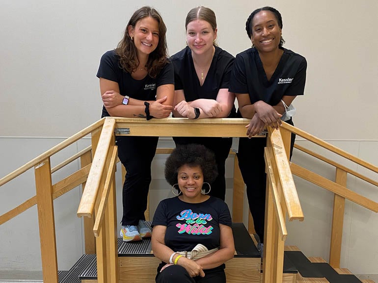 Photo of Pam Ivey and her therapists in the therapy gym at Kessler Institute for Rehabilitation.